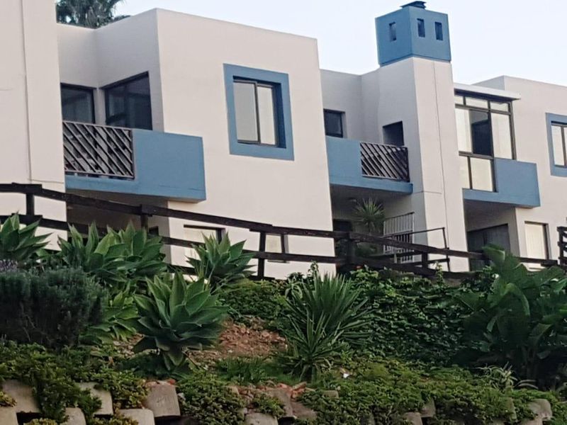 Rear elevation of a multi-level apartment complex featuring private balconies with metal railings and a prominent chimney stack.