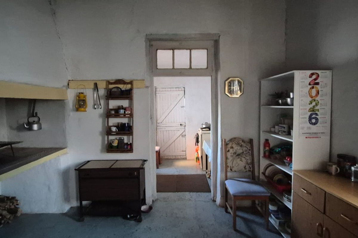Rustic kitchen area featuring a traditional built-in hearth, exposed masonry walls, and a doorway leading to an adjacent room.