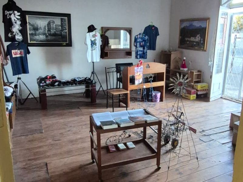 A living area featuring original timber floorboards and a dark timber ceiling, with access to an exterior space through a glass panel door.