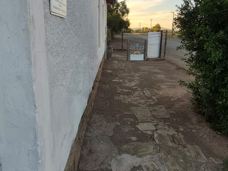 Side exterior view of the property featuring a stone paved walkway and plastered wall finish leading towards the front gate.