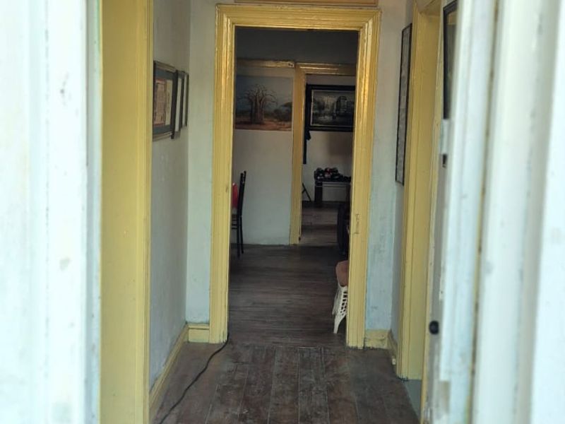 A traditional hallway featuring original timber flooring and classic architraves, leading through to adjoining living spaces.