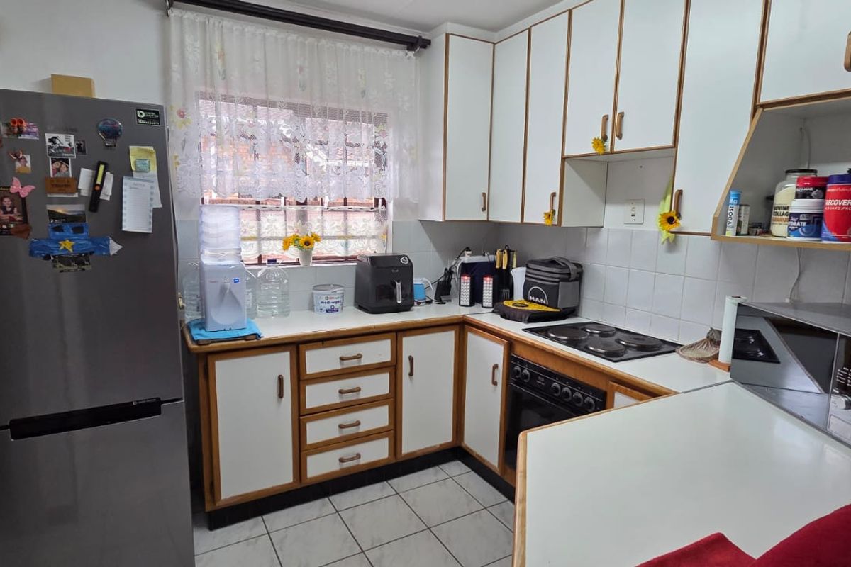 A functional kitchen featuring white laminate cabinetry, tiled backsplash, built-in oven with electric hob, and tiled flooring.