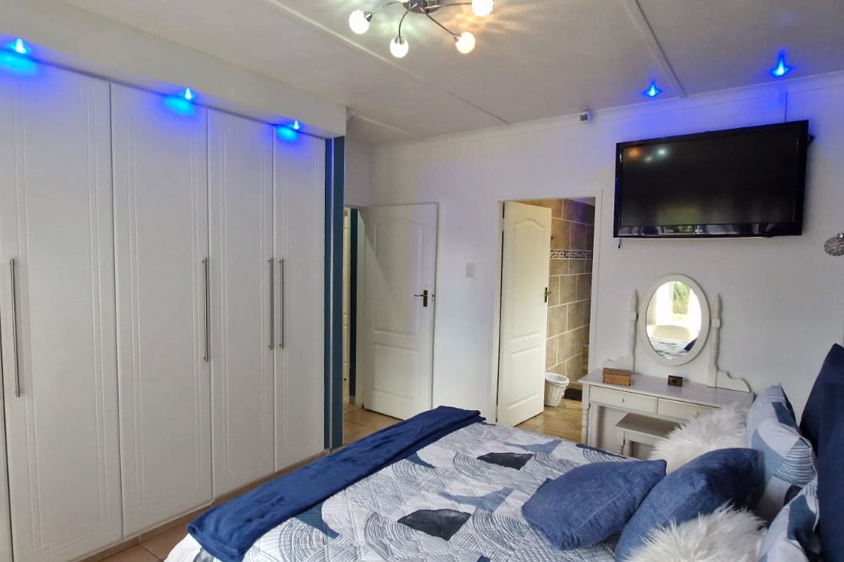 A well-maintained bedroom featuring extensive built-in cabinetry with integrated accent lighting and direct access to an en-suite bathroom.