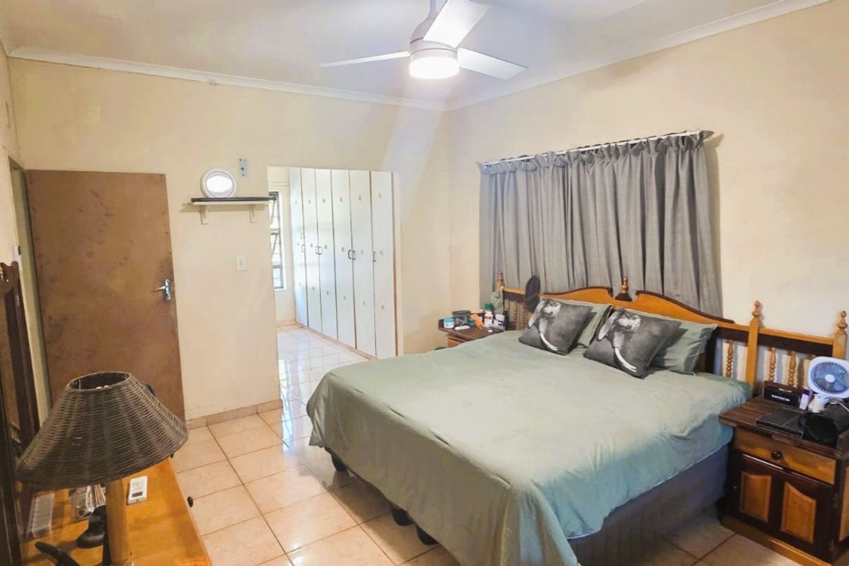 A functional bedroom featuring tiled flooring, a ceiling fan, and extensive built-in cupboard storage.