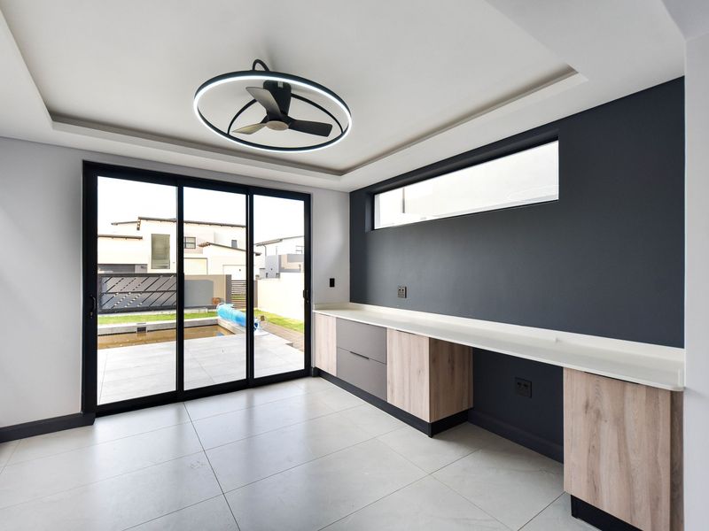 Modern living space featuring built-in cabinetry, stone countertops, sleek tiled flooring, and large sliding glass doors opening to the outdoor patio area.