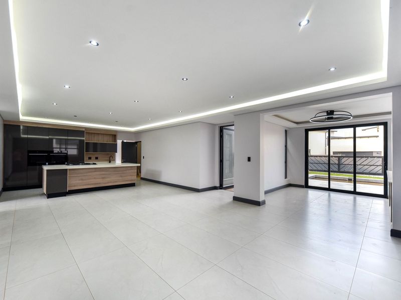 Spacious open-plan living area featuring modern kitchen cabinetry, a central island, recessed lighting, and large sliding glass doors leading to the exterior.
