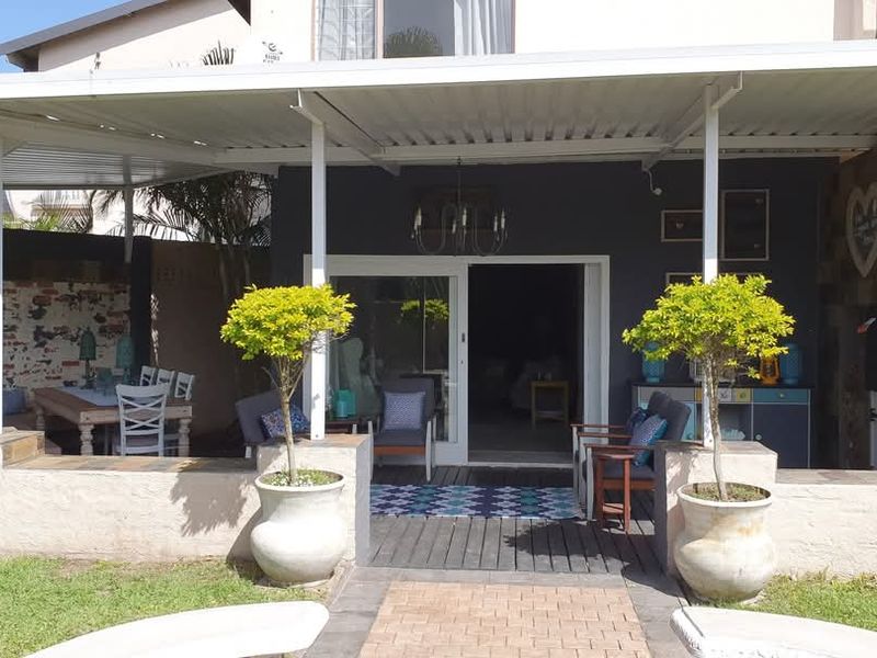 A covered outdoor patio area featuring a built-in braai, stone cladding, and direct access to the interior through sliding doors.