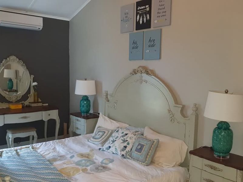 A well-maintained bedroom featuring a vaulted ceiling and a wall-mounted split-system air conditioning unit.