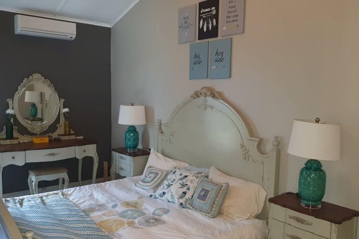 A well-maintained bedroom featuring a vaulted ceiling and a wall-mounted split-system air conditioning unit.