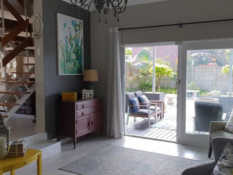 Spacious living area featuring an open staircase, tiled flooring, and large sliding glass doors providing seamless access to the outdoor patio and garden.