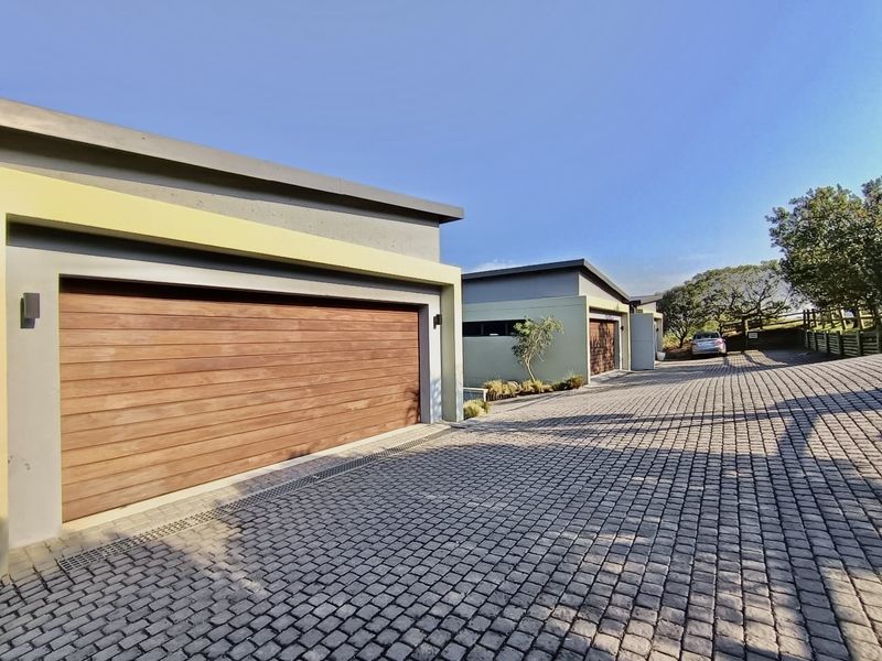 Modern townhouse exterior featuring timber garage doors and a well-maintained paved driveway leading to the property entrance.