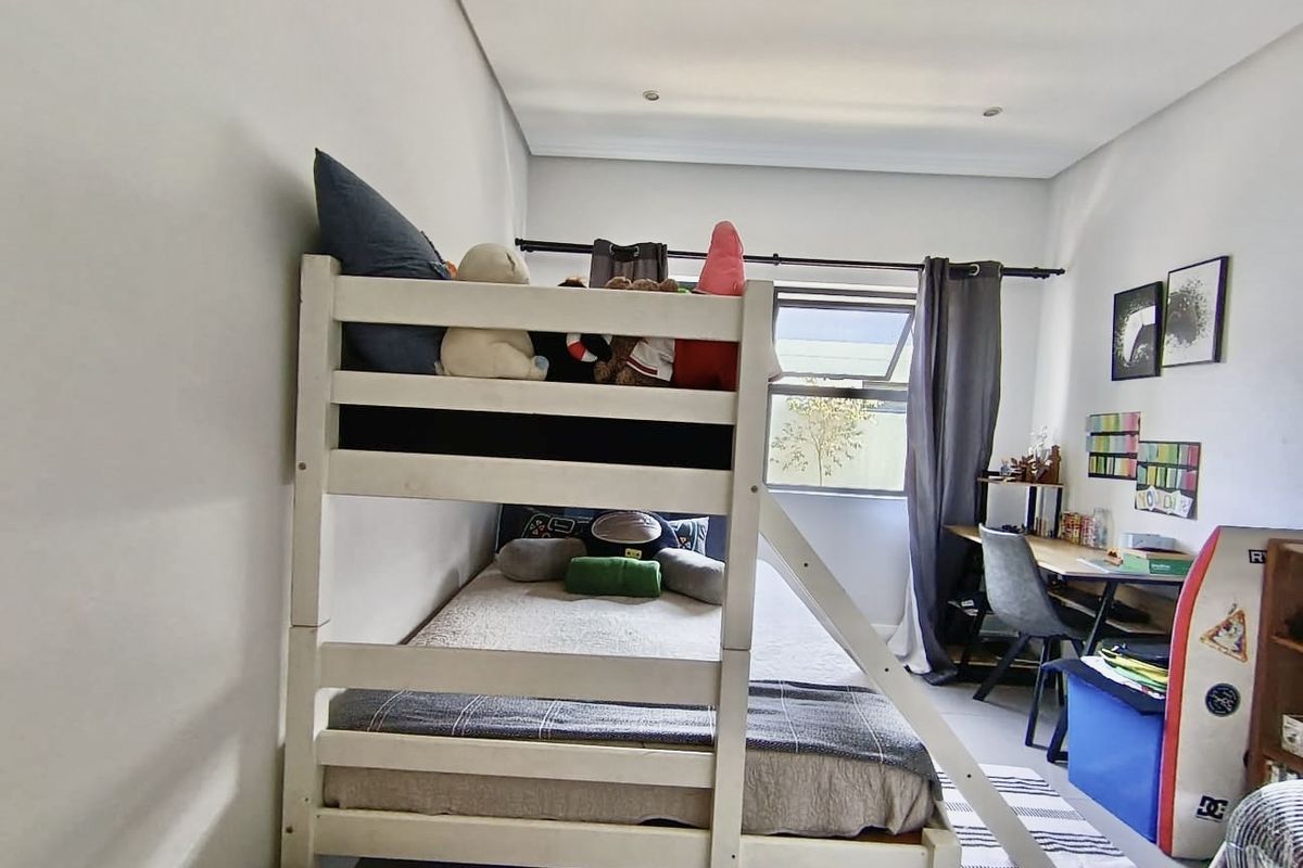 A functional bedroom featuring recessed downlighting and a top-hung window with curtain rod, providing natural light and a neutral backdrop.