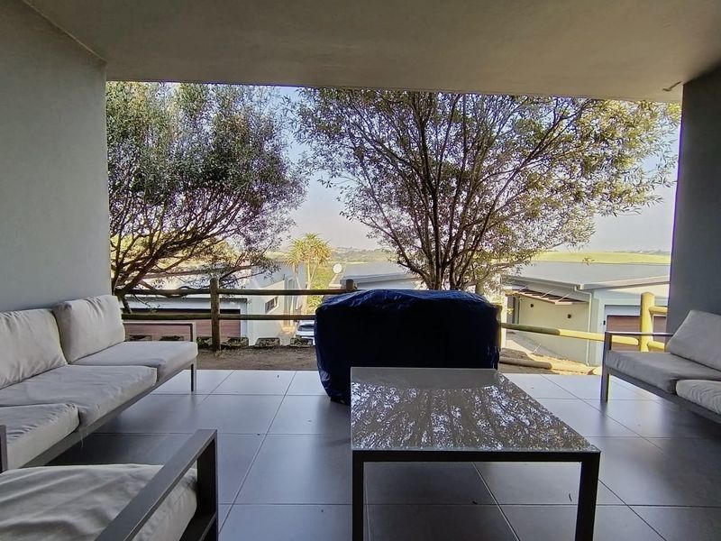 A covered outdoor patio featuring tiled flooring and a timber post and rail fence, offering views of the surrounding property.
