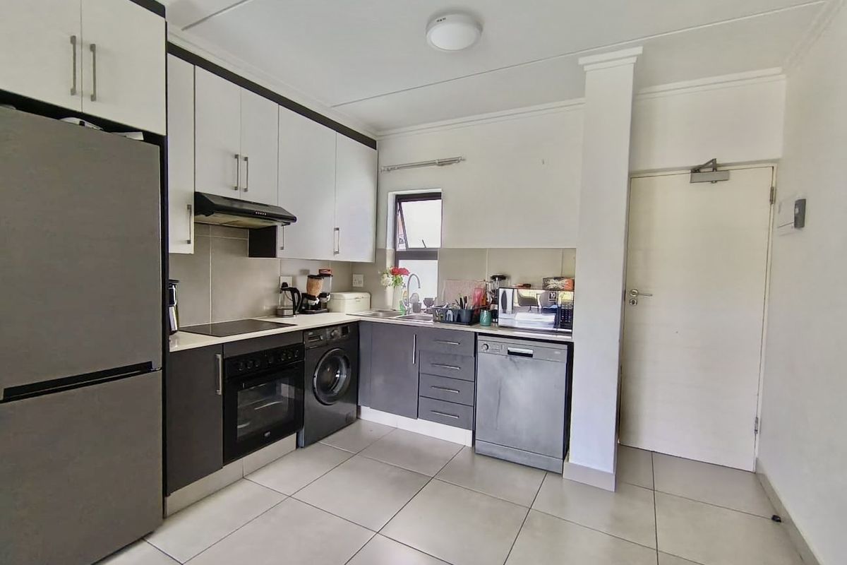 A functional kitchen featuring modern two-tone cabinetry, integrated appliances, tiled flooring, and a practical layout with ample storage and workspace.