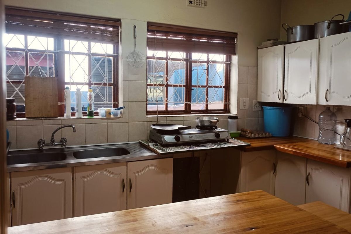 A functional kitchen featuring wooden countertops, built-in cabinetry, and a double basin stainless steel sink with natural light from windowed exterior views.