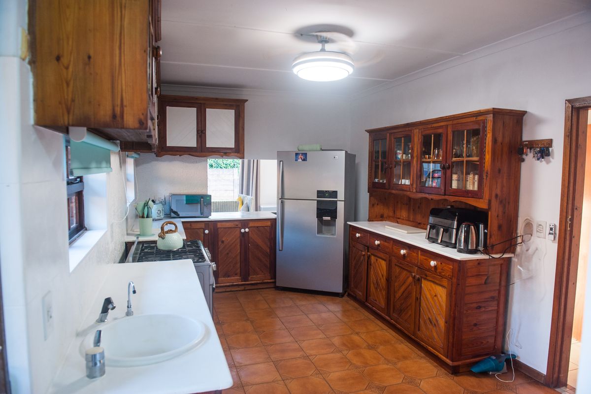 A functional kitchen featuring extensive wooden cabinetry, a built-in hutch, gas stove, and tiled flooring, offering a traditional aesthetic with potential for modernization.