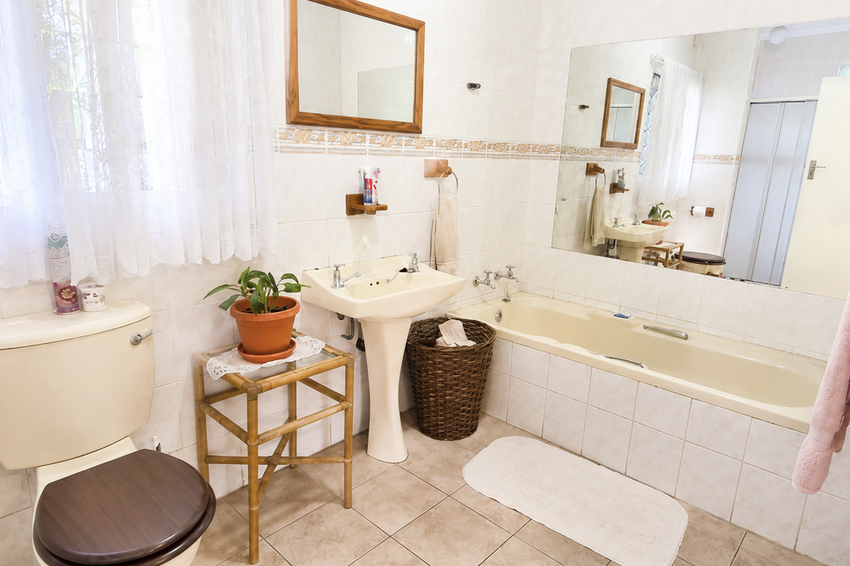 A functional bathroom featuring a pedestal sink, a built-in bathtub, and tiled walls with a decorative border.