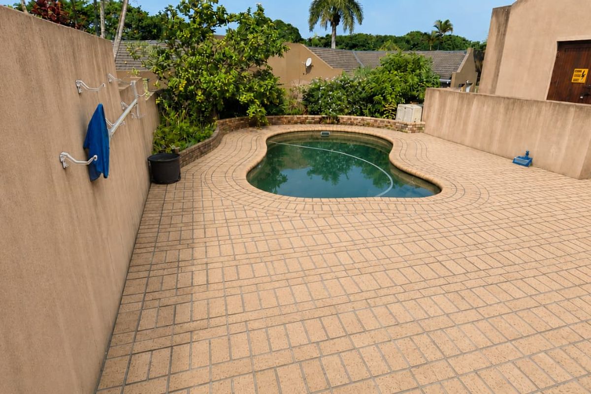 Private outdoor pool area featuring paved patio space, perimeter walls, and a built-in security gate, offering a functional space for outdoor relaxation.