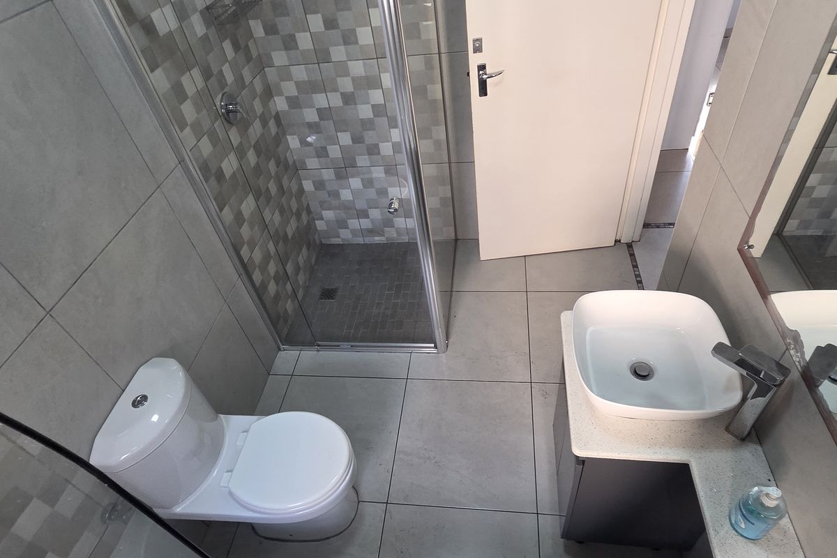 Modern bathroom featuring a glass-enclosed shower, tiled walls, a vessel sink vanity, and contemporary floor tiling.