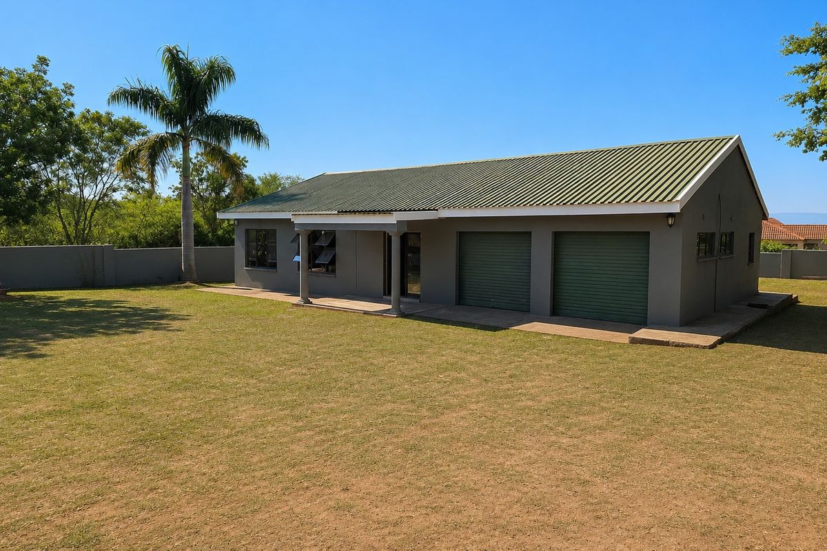 A well-maintained single-story house featuring a corrugated metal roof, double garage with roller shutter doors, and a covered patio overlooking a spacious lawn.