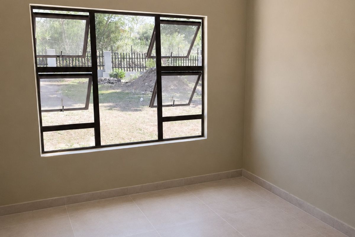 A clean, empty bedroom featuring neutral tiled flooring, modern aluminium window frames, and freshly painted walls, ready for personalization.