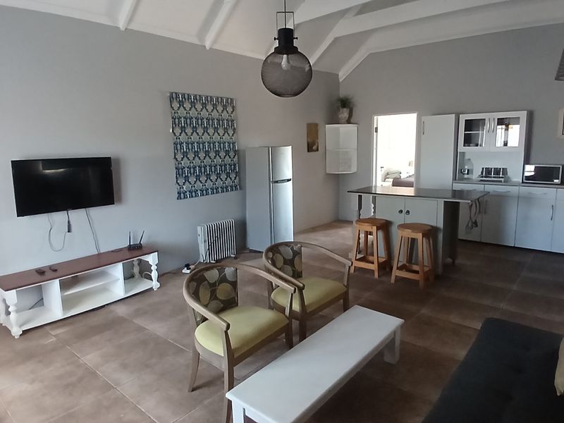 Open-plan living and kitchen area featuring vaulted ceilings, tiled flooring, and a central kitchen island with breakfast bar seating.