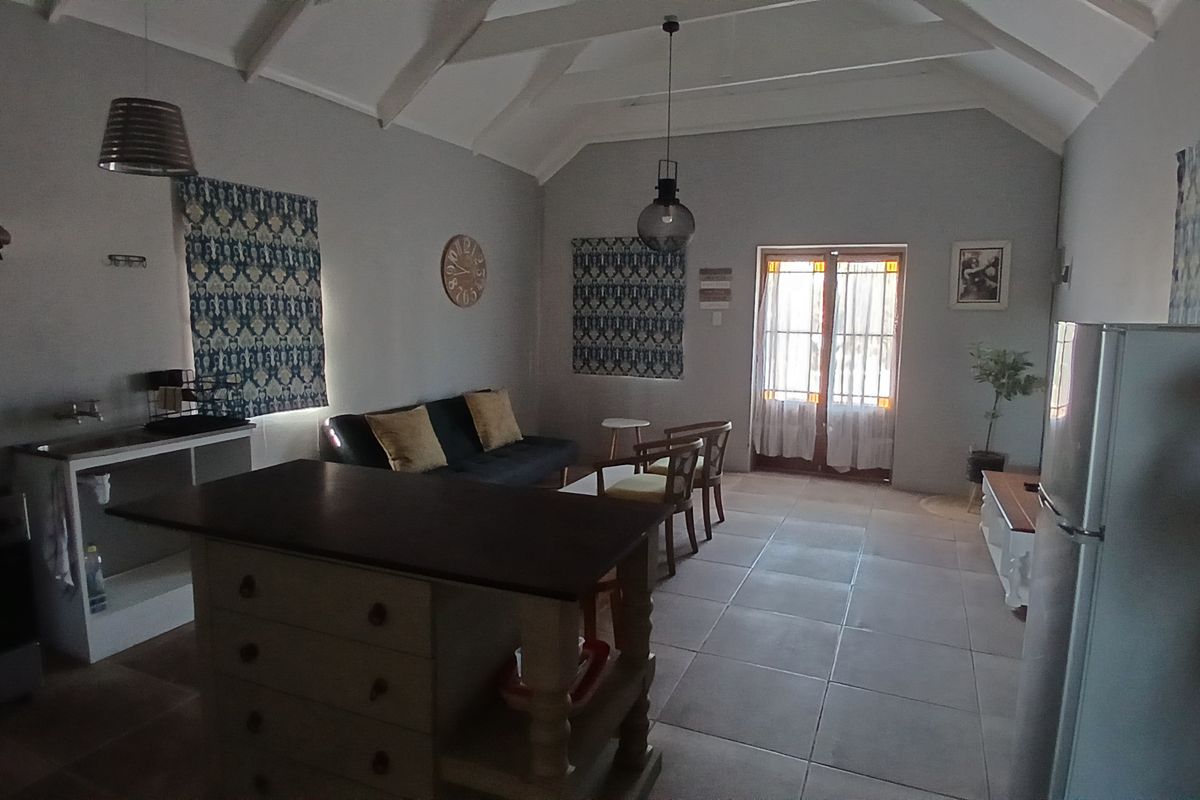 Open-plan living area featuring a vaulted ceiling, tiled flooring, kitchen island, and direct access to the outdoors through classic french doors.