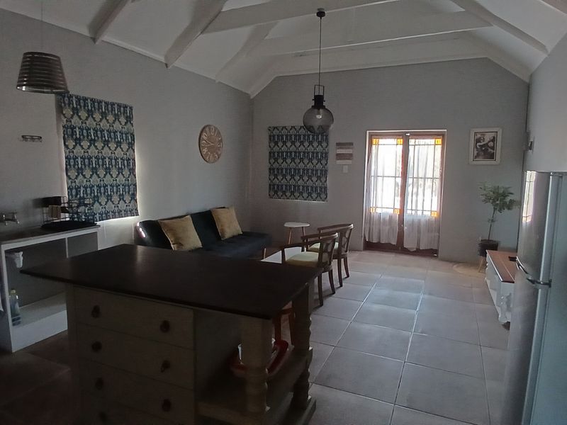 Open-plan living area featuring a vaulted ceiling, tiled flooring, kitchen island, and direct access to the outdoors through classic french doors.