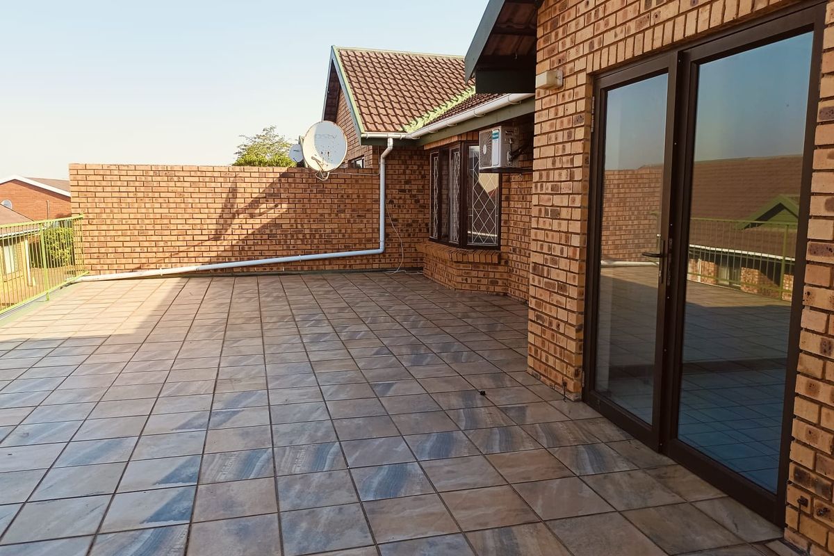 A spacious, tiled outdoor patio area featuring brick wall construction and direct access to the interior through sliding glass doors.