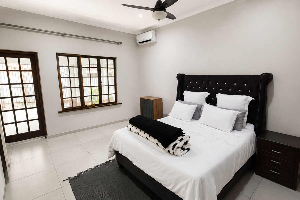 A well-maintained bedroom featuring tiled flooring, built-in cupboards, a ceiling fan, and a split-system air conditioner, with direct access to an outdoor area.