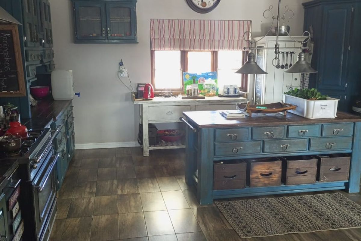 A rustic-style kitchen featuring a large central island, dark blue cabinetry, a gas range, and wood-look tiled flooring.