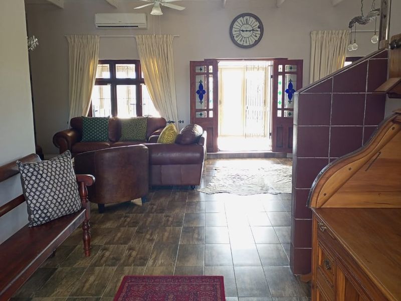 Spacious living area featuring high vaulted ceilings with exposed trusses, tiled flooring, a fireplace, and direct access to the exterior through stained glass doors.
