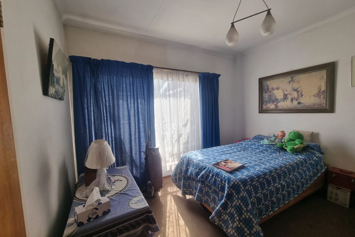 A standard bedroom featuring a sliding glass door with curtains and a central ceiling light fixture.