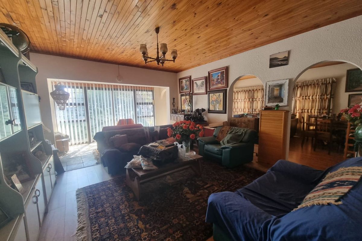 Spacious living room featuring a timber tongue and groove ceiling, arched architectural details, and large sliding glass doors providing access to the outdoor area.