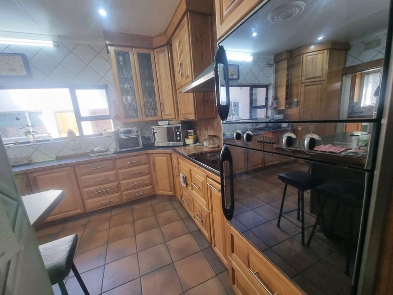 A traditional kitchen featuring extensive wooden cabinetry, granite countertops, tiled flooring, and built-in oven with extractor fan.