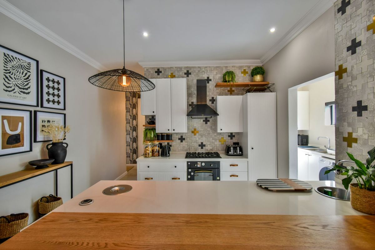 Modern kitchen featuring white cabinetry, gas cooktop, integrated oven, extractor fan, and a stone-topped island with an undermount sink.