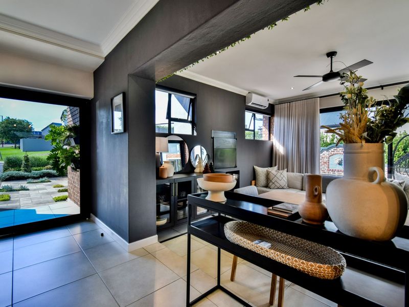 Modern open-plan living area featuring tiled floors, a ceiling fan, split-system air conditioning, and large glass doors providing seamless access to the outdoor space.