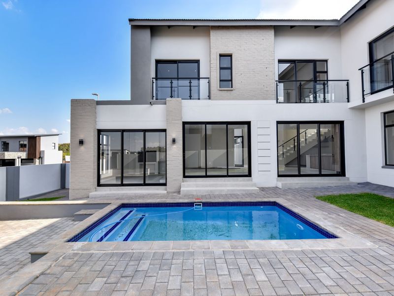 Modern double-story residence featuring a rear patio, swimming pool, and large sliding glass doors providing seamless indoor-outdoor flow.