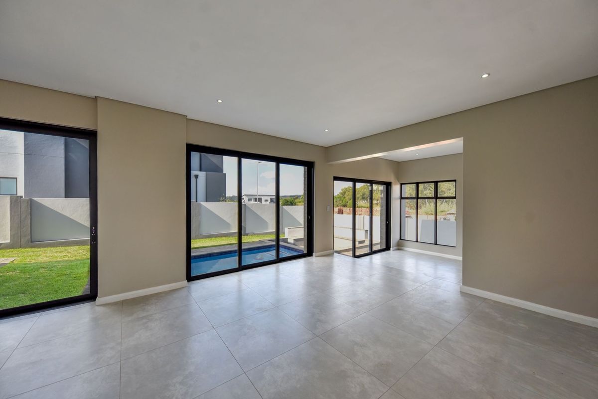 Spacious, modern open-plan living area featuring large format floor tiles, recessed lighting, and expansive aluminium sliding doors providing direct access to the pool area.