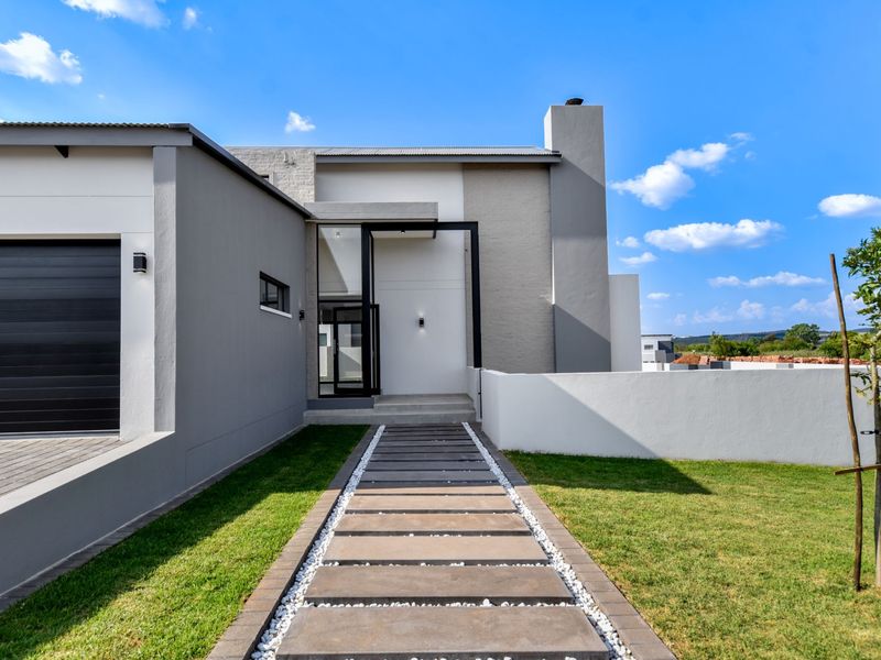 Modern front facade featuring a paved walkway, integrated garage, and clean architectural lines with a well-maintained lawn.