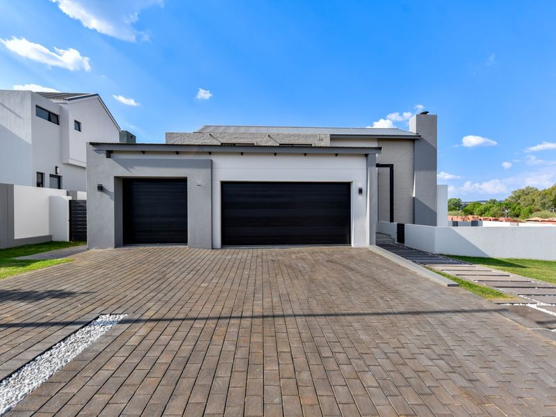 Modern front elevation featuring a paved driveway, double and single garage doors, and clean architectural lines.