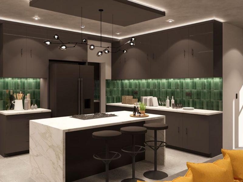 Modern kitchen featuring dark cabinetry, a marble-topped island with integrated cooktop, green tiled backsplash, and sophisticated recessed and pendant lighting.