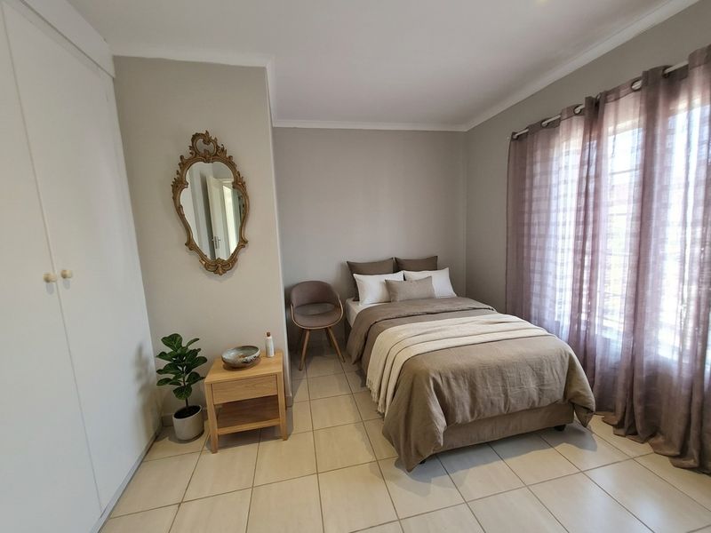 A well-maintained bedroom featuring neutral wall tones, tiled flooring, and a built-in wardrobe, offering a clean and functional living space.
