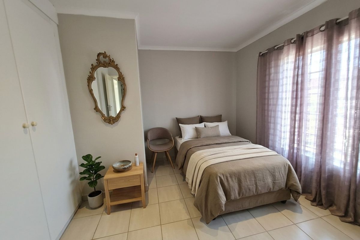 A well-maintained bedroom featuring neutral wall tones, tiled flooring, and a built-in wardrobe, offering a clean and functional living space.