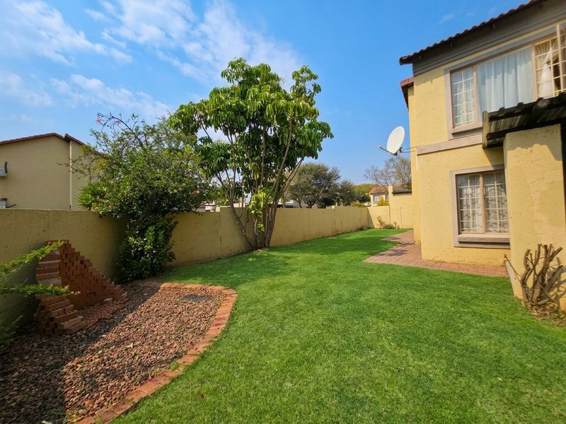 A private rear garden featuring a well-maintained lawn, paved pathway, and perimeter boundary wall, providing a secure outdoor space for the townhouse.
