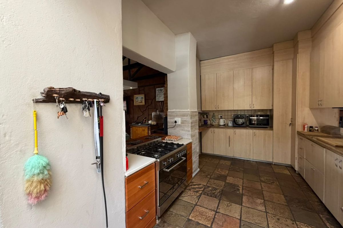 A functional kitchen featuring light wood cabinetry, a gas stove with oven, and durable stone tile flooring, with an open flow to the adjacent living area.