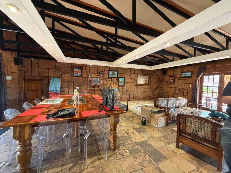 Spacious open-plan living area featuring exposed timber roof trusses, stone-clad walls, and durable tiled flooring with direct access to the outdoors.