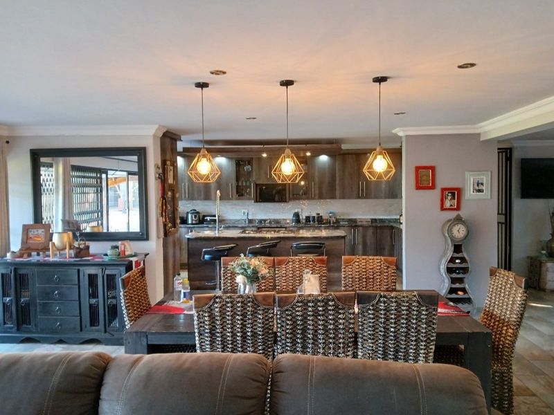 Spacious open-plan living and dining area featuring a modern kitchen with a central island, dark wood cabinetry, and contemporary pendant lighting.