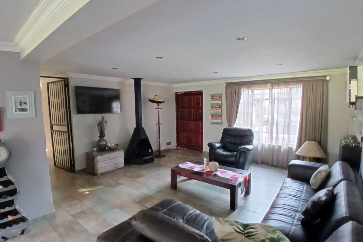 Spacious living room featuring tiled flooring, recessed downlights, decorative cornicing, and a modern freestanding fireplace, providing a comfortable and well-lit area.