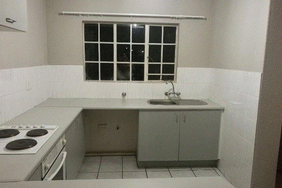 A functional kitchen featuring built-in cabinetry, laminate countertops, a stainless steel sink, and an integrated electric hob and oven with tiled splashbacks.